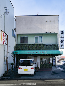 グリーン色の店舗用テントに書かれた「御食事処 玉山食堂」